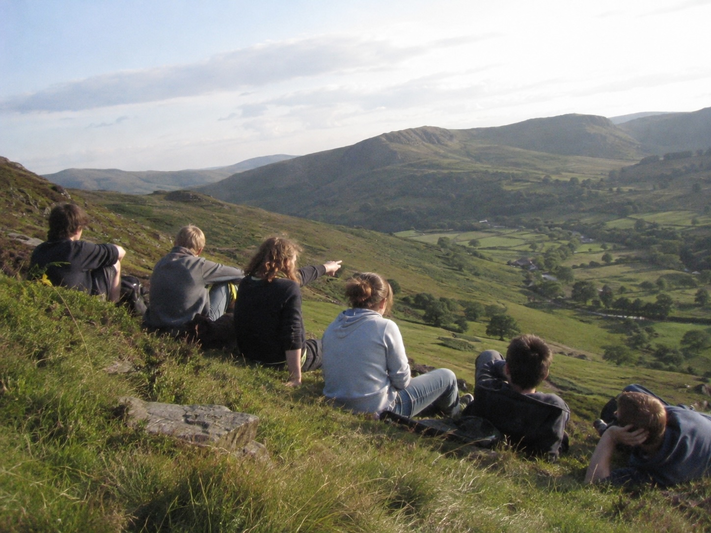 Latimer Summer School students sitting on a hillside in Wales, looking out over the valley